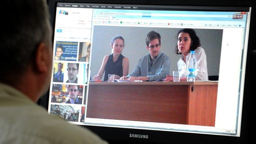 Un homme regarde une photo de l'ex-consultant du renseignement américain Edward Snowden (c) pendant sa rencontre avec des défenseurs des droits de l'homme, le 12 juillet 2013 à Moscou