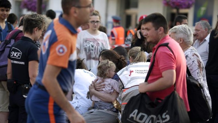 Une femme serre son enfant dans ses bras entourée de secouristes sur les lieux de l'accident de train meurtrier de Brétigny-sur-Orge, le 12 juillet 2013