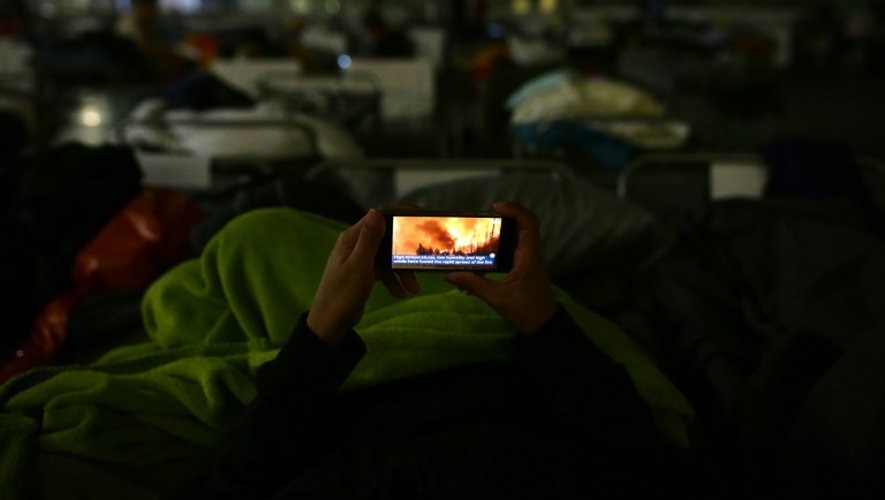 Une personne regarde des images de l'incendie sur son téléphone portable, dans un logement de fortune pour les personnes évacuées de Fort McMurray, au Canada, le 5 mai 2016