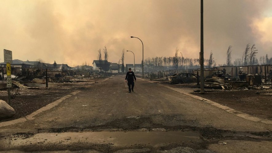 Photo fournie par les autorités canadiennes montrant, le 5 mai 2016 un policier marchant dans une rue de Fort McMurray où de nombreuses habitations ont été ravagées par des incendies