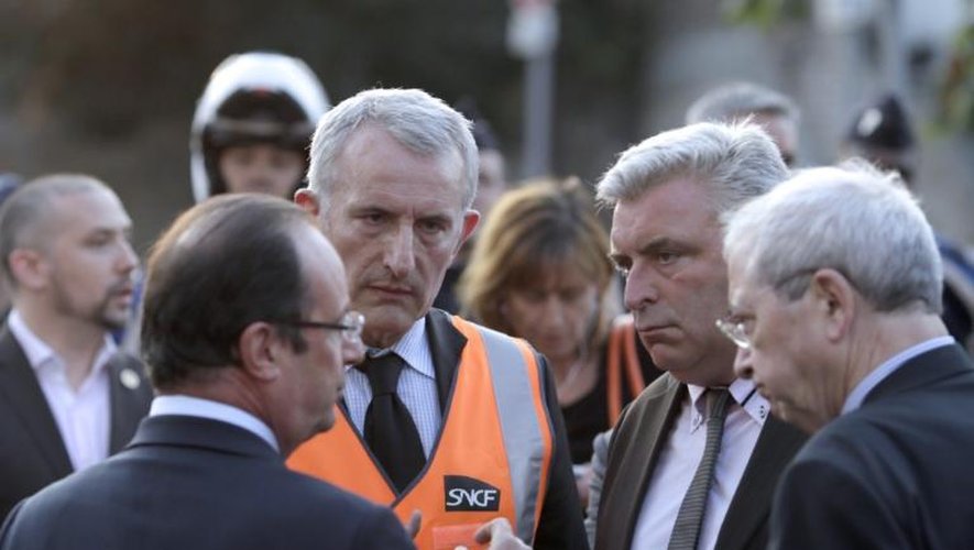 Le président François Hollande (à gauche) s'entretient avec le ministre des Transports Frédéric Cuvillier (2e à droite) et le le président de la SNCF Guillaume Pepy, sur les lieux de l'accident à Brétigny-sur-Orge (Essonne), le