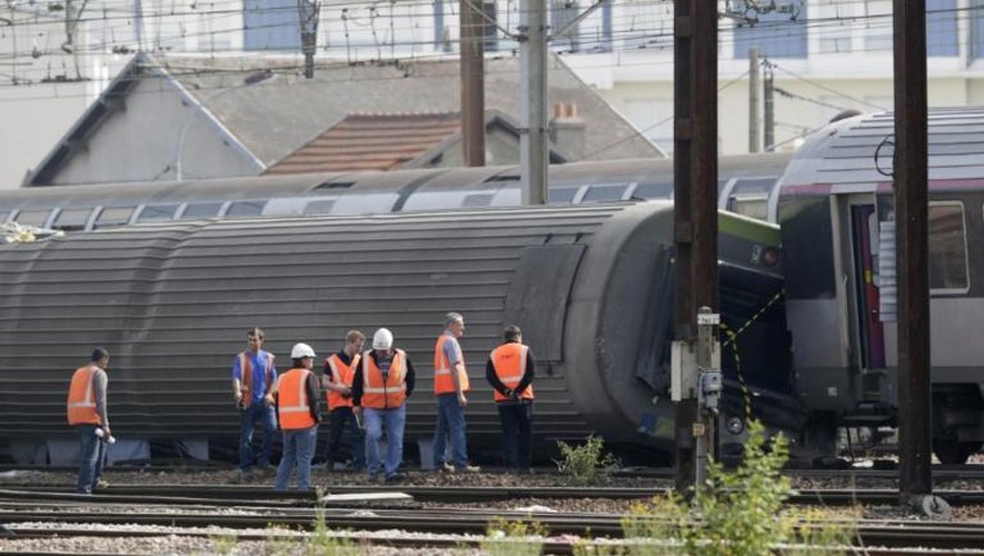 Des personnes inspectent les rails, à Brétigny-sur-Orge (Essonne), après le déraillement d'un train, le 13 juillet 2013