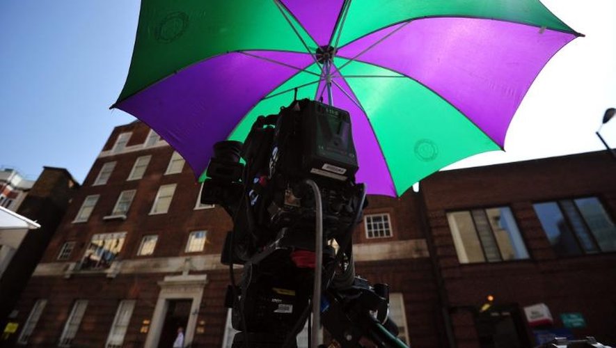 Une caméra vidéo positionnée devant l'hôpital Lindo Wing of Saint Mary est abritée sous un parapluie, le 12 juillet 2013 à Londres