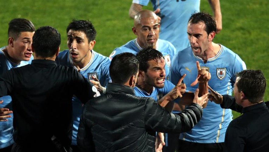 Les joueurs de l'équipe d'Uruguay Jose Maria Gimenez, Jorge Fucile, Alvaro Gonzalez et Diego Godin se disputent avec l'arbitre et les juges de touche pendant la match de quart de finale de la Copa America à Santiago le 24 juin 2015