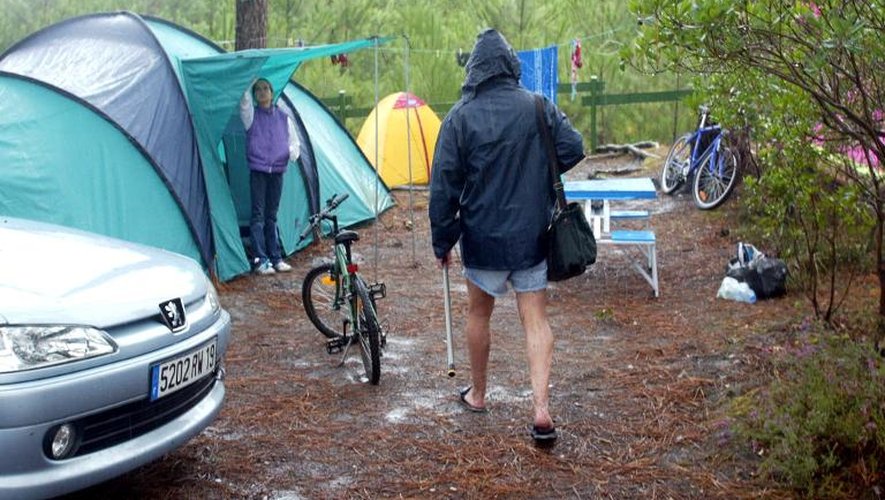 Un touriste rejoint sa tente sous la pluie, le 10 août 2002 au camping du Tedey près de Lacanau