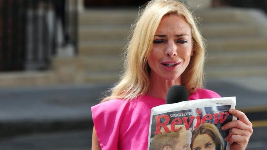Une journaliste brandit un journal devant la clinique où devrait accoucher Kate, à Londres le 14 juillet 2013