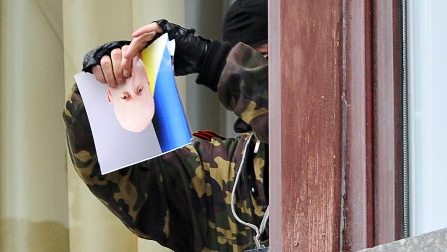 Un militant pro-russe déchire le portrait d'un responsable ukrainien après la prise de la préfecture de région à Lougansk, le 29 avril 2014