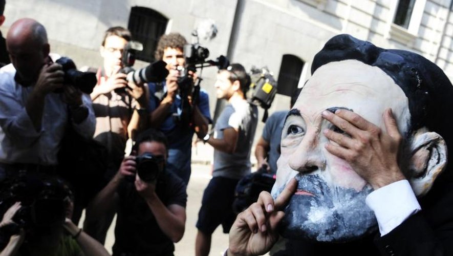 Un manifestant porte un masque à l'effigie du Premier ministre Mariano Rajoy, près du tribunal de l'Audience nationale, le 15 juillet 2013 à Madrid
