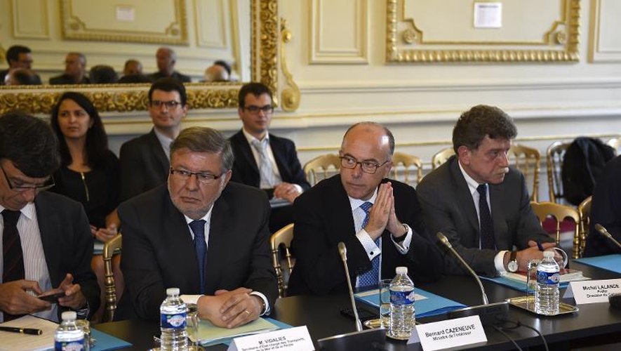 Le ministre de l'intérieur Bernard Cazeneuve (au c.) et le secrétaire d'Etat aux transports Alain Vidalies (à g.) recoivent une délégation de l'intersyndicale des chauffeurs de taxi, le 25 juin 2015 à Paris