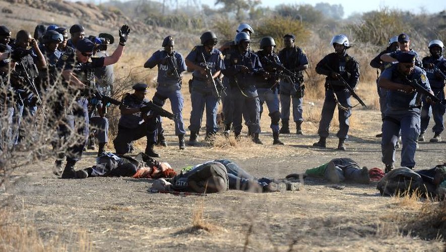 Des policiers sud-africains se tiennent près des corps de mineurs tombés après qu'ils aient ouvert le feu lors d'affrontements avec les manifestants à la mine de Marikana, le 16 août 2012 en Afrique du Sud