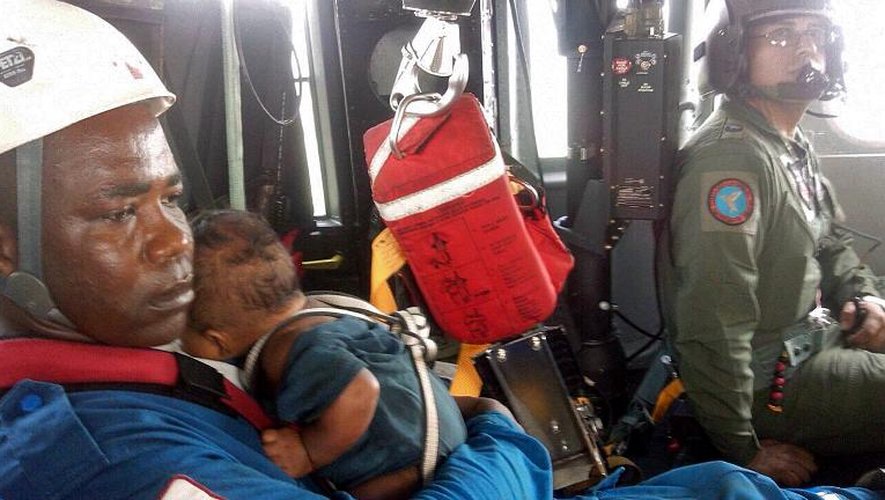 Photo remise le 24 juin 2015 par les forces aériennes colombiennes du secouriste de la Croix-Rouge, Acisclo Renteria, avec le bébé sur son ventre après l'avoir retrouvé, lui et sa mère, dans une zone reculée de la province de Choco, en Colombie
