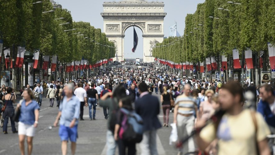 Des passants sur l'avenue des Champs-Elysées à Paris le 8 mai 2016 à l'occasion d'une journée sans voiture désormais chaque premier du dimanche du mois pour lutter contre la pollution