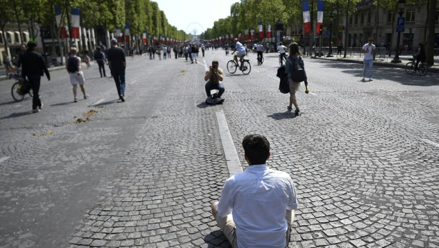Un homme se fait photographier sur l'avenue des Champs-Elysees à Paris le 8 mai 2016 à l'occasion d'une journée sans voiture sur la célèbre avenue qui se reproduira un dimanche par mois