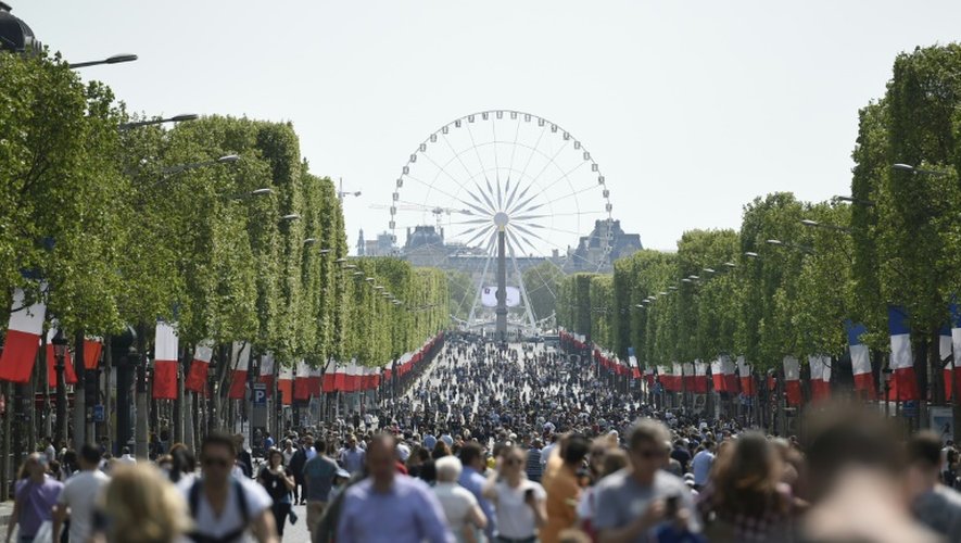 Des passants sur l'avenue des Champs-Elysées à Paris le 8 mai 2016 à l'occasion d'une journée sans voiture sur la célèbre avenue parisienne appelée à se répéter un dimanche par mois