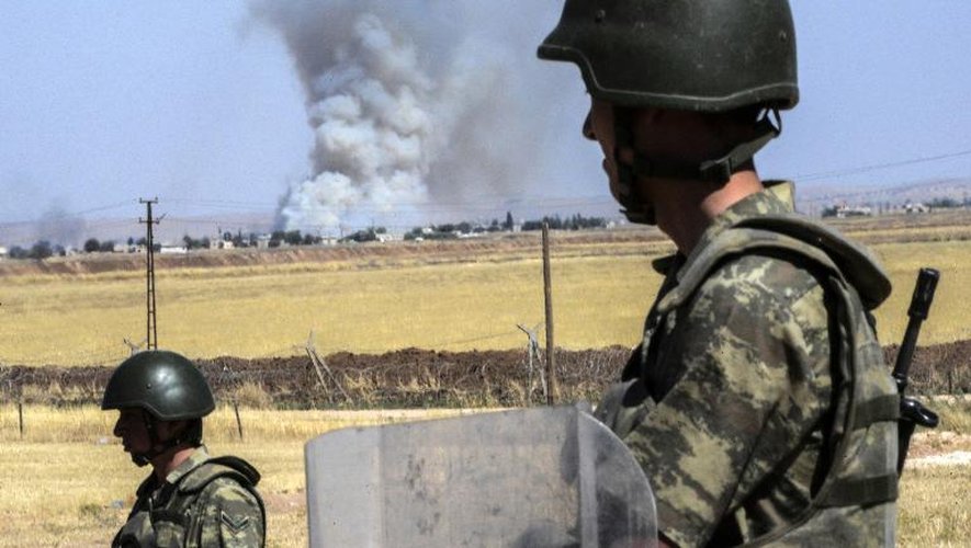 Des soldats turcs observent, par-dessus la frontière avec la Syrie, la fumée des combats dans Kobané, le 25 juin 2015 près de Suruc, en Turquie
