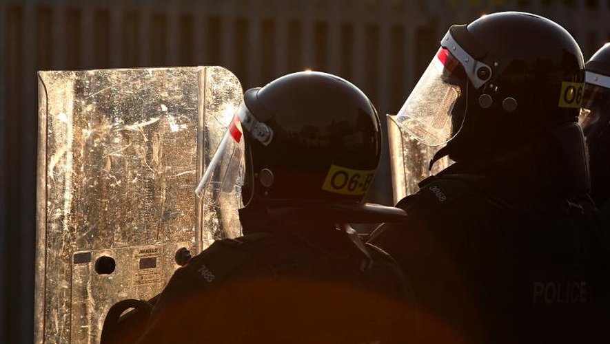 Des policiers se protègent contre des tirs de projectiles des manifestants protestants à Belfast, le 13 juillet 2013