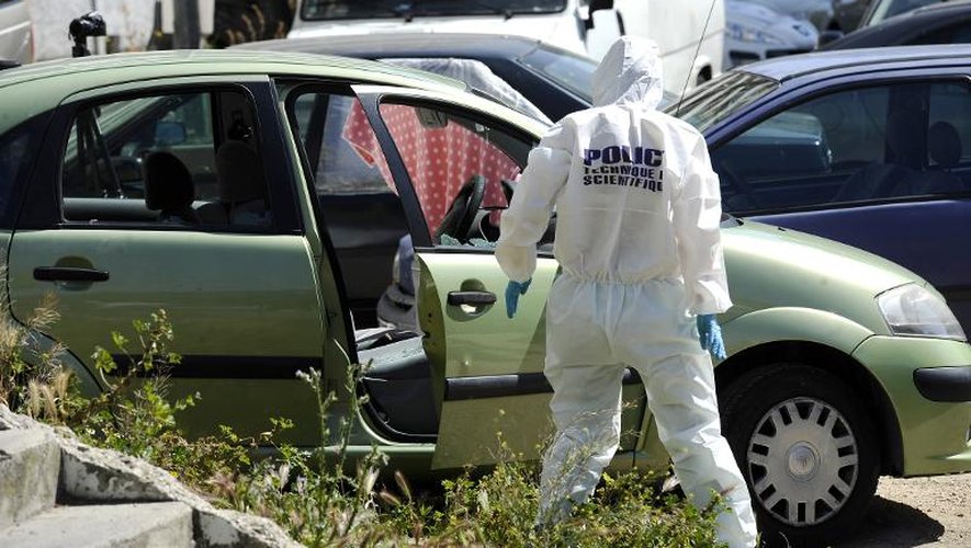 Un policier devant un voiture où un homme a été tué par balles le 24 avril 2014 à "La Busserine" à Marseille