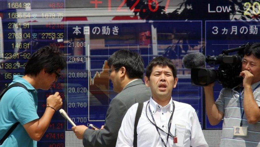 Un journaliste de la télévision devant un tableau des changes le 24 juin 2015 à Tokyo