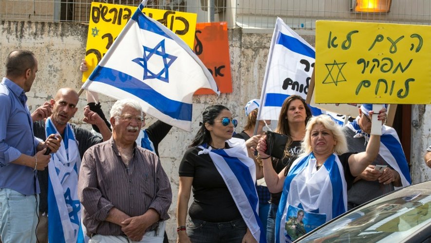 Des Israëliens brandissent des drapeaux et des pancartes en hébreu "Le peuple n'abandonne pas un soldat" devant l'entrée du tribunal militaire à Tel Aviv où se déroule le procès d'Elor Azaria le 9 mai 2016