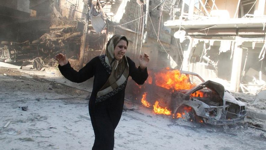 Une femme passe devant une voiture en feu à Alep, le 1er mai 2014 après un raid aérien attribué aux forces gouvernementales