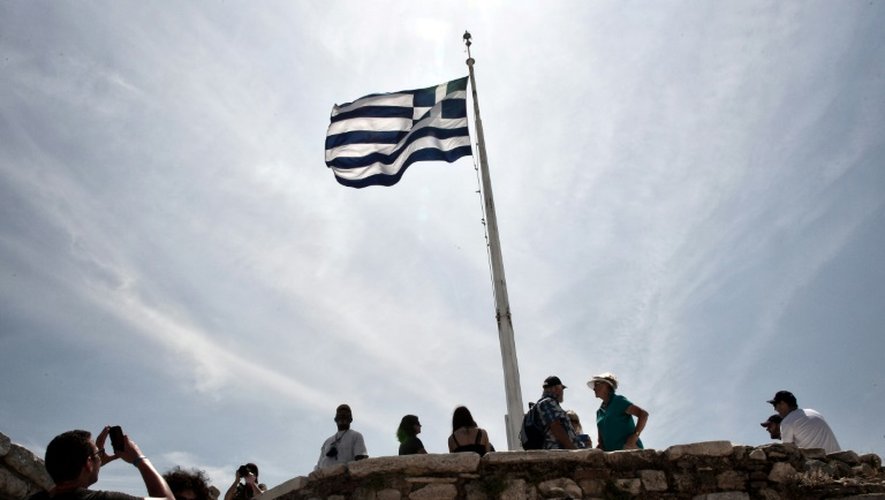 Des touristes près d'un drapeau grec sur l'Acropole à Athènes le 9 mai 2016