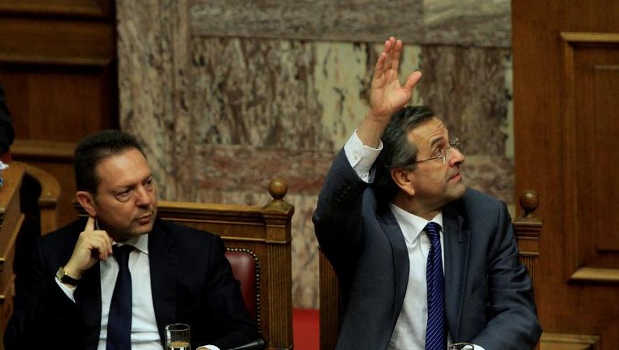 Le Premier ministre grec Antonis Samaras (d) lève la main pour voter, à côté de son ministre des Finances Yannis Stournaras, le 18 juillet 2013 au Parlement à Athènes