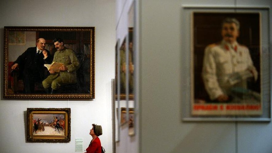 Une femme regarde un tableau représentant Lénine et Staline, lors de l'exposition "Le mythe du chef bien-aimé", le 2 avril 2014 à Moscou