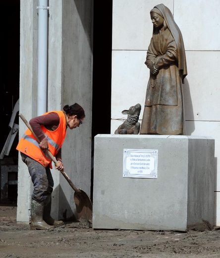 Une femme enlève de la boue autour d'une statue, le 20 juin 2013 à Lourdes