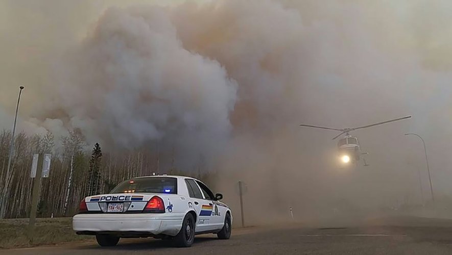 Une photo fournie par la police montée d'Alberta au Canada, montrant une voiture de police et un hélicoptère pris dans le nuage de fumée des incendies de Fort McMurray, le 7 mai 2016