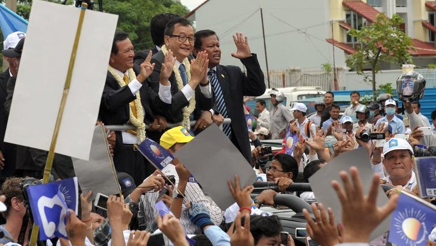 Le chef de l'opposition Sam Rainsy (c) et Kem Sokha (g) dans les rues de Phnom Penh devant des milliers de partisans, le 19 juillet 2013