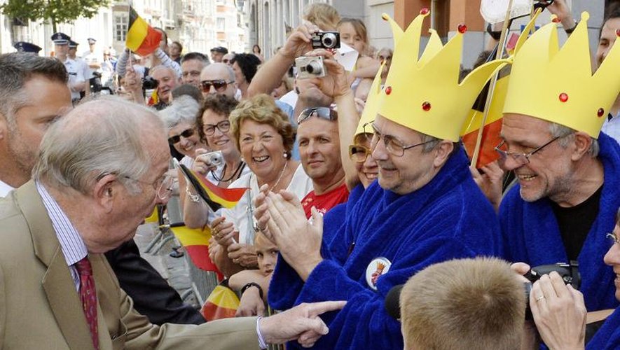 Albert II échange quelques mots avec des personnes déguisées comme le roi des Belges, en robe de chambre, imaginé par le caricaturiste Pierre Kroll, lors d'un déplacement à Eupen, le 18 juillet 2013