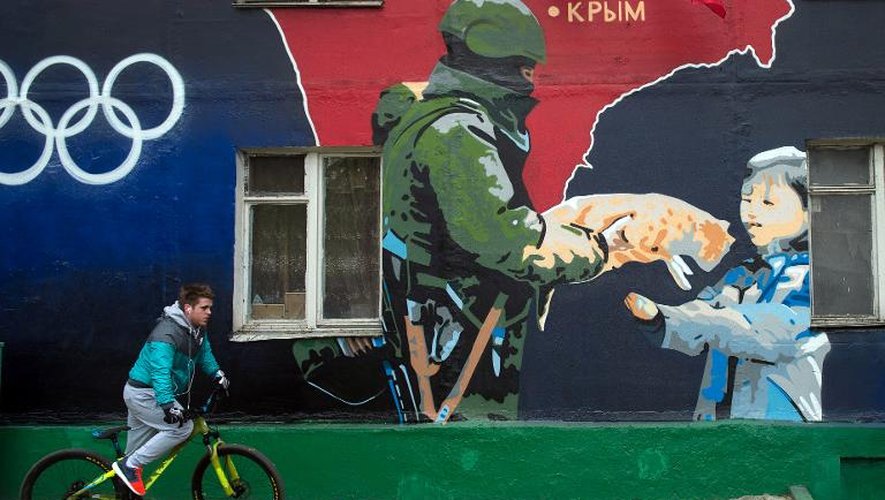 Un garçon passe devant une peinture murale montrant un soldat russe, à Moscou, le 4 mai 2014
