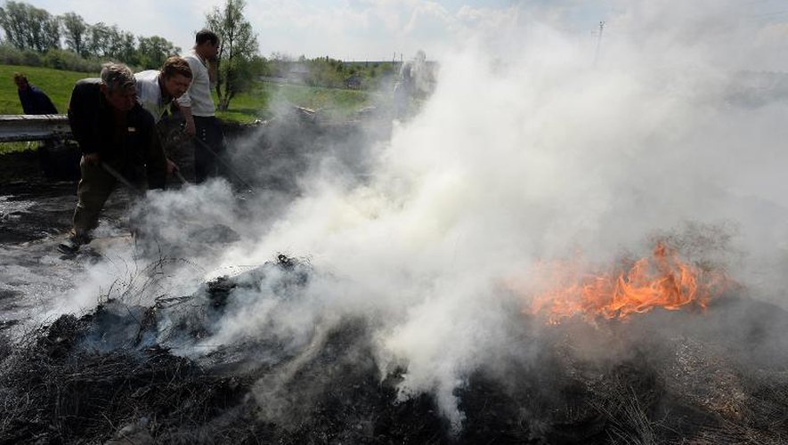 Des activistes pro-russes éteignent un incendie sur leur barricade, le 4 mai 2014 près de Slaviansk, le bastion des insurgés armés pro-russes