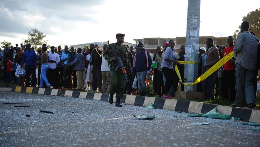 Un soldat patrouille à Nairobi, alors que des habitants se regroupent sur le site de deux explosions, le 4 mai 2014 au Kenya