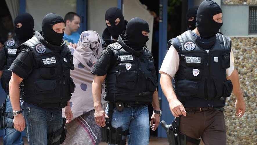 Des policiers sortent de l'immeuble de Saint-Priest, dans le Rhône, où vivait l'auteur présumé de l'attaque d'une usine en Isère, où ils ont interpellé une femme non identifiée, le 26 juin 2015
