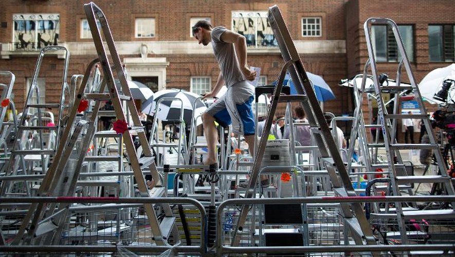 Un photographe escalade les escabeaux installés devant la maternité de l'hôpital St Mary, à Londres le 17 juillet 2013