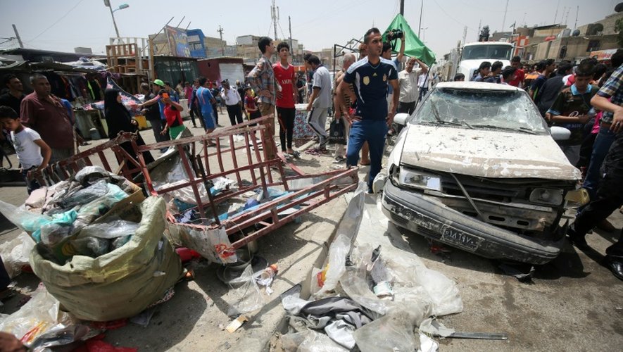 Des passants constatent les dégâts après l'explosion d'une voiture piégée près d'un marché du grand quartier chiite Sadr City, dans le nord de Bagdad, qui a fait au moins 34 morts le 11 mai 2016