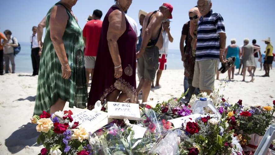 Des touristes et des Tunisiens contemplent les fleurs déposées sur la plage en hommage aux victimes de la tuerie de l'hôtel Riu Imperial Marhaba, à Port el Kantaoui, le 28 juin 2015
