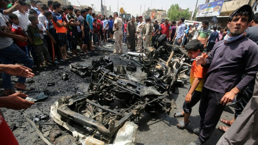Des Irakiens regardent les dégâts causés par un voiture piégée à Sadr City, un quartier chiite de Bagdad le 11 mai 2016