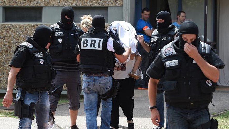 Les forces spéciales de la BRI escortent une femme et un enfant dans les bras, le 25 juin 2015 dans la ville de Saint-Priest, près de Lyon