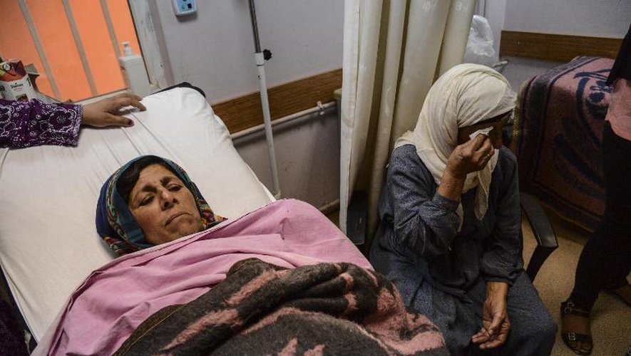 Une femme sur un lit d'hôpital à Suruc, en Turquie, entrouée de proches, après avoir été blessée dans la ville syrienne de Kobané, le 26 juin 2015