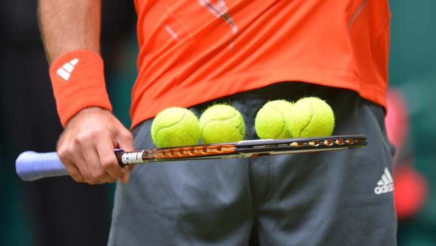 Un joueur de tennis, sa raquette et quatre balles