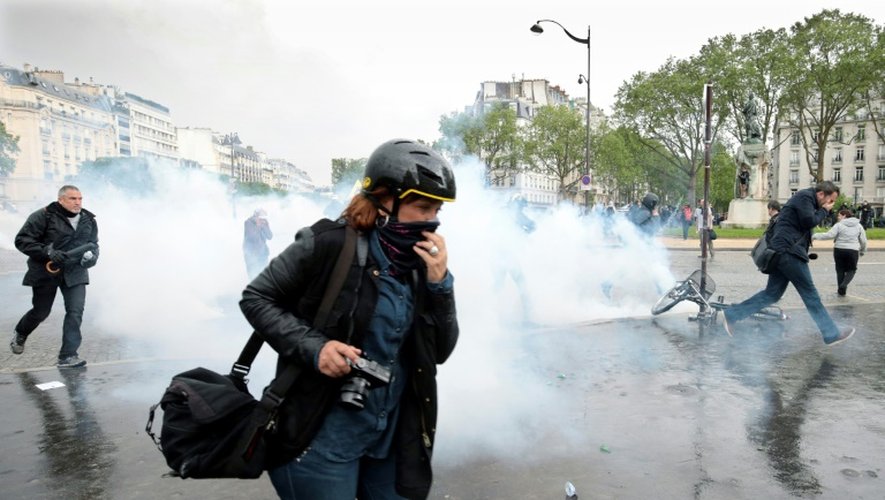 Les manifestants tentent d'échapper au nuage de gaz lacrymo lors des manifestations contre la loi Travail, à Paris le 12 mai 2016
