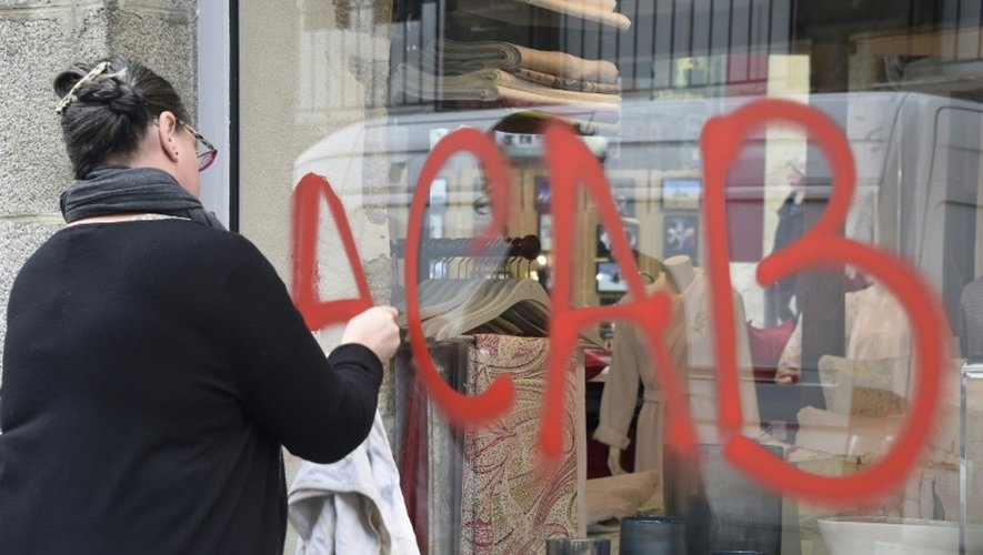 Une femme nettoie un graffiti sur sa boutique à Rennes, le 14 mai 2016
