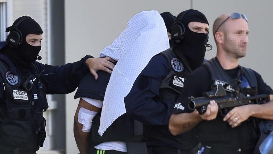 Yassin Salhi escorté par des policiers alors qu'il vient de récupérer son passeport dans son appartement de Saint-Priest avant d'être transféré à Paris, le 28 juin 2015