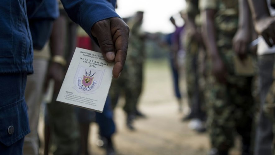 Un policier tient sa carte d'électeur dans une file d'attente devant un bureau de vote à Bujumbura, le 29 juin 2015
