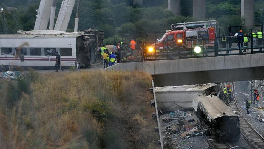 Des secouristes inspectent le 25 juillet 2013 l'un des wagons détruits à la suite d'un accident de train quelques heures auparavant près de Saint-Jacques de Compostelle, en Espagne