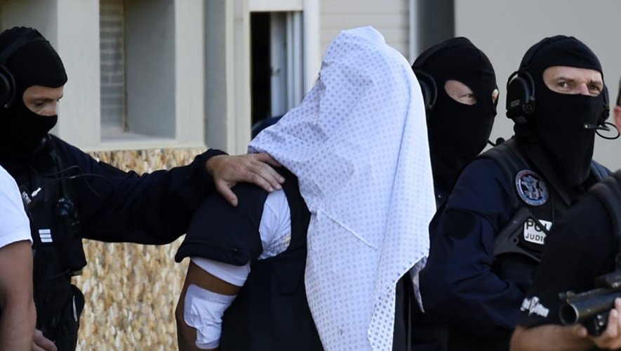 Yassin Salhi entre des policiers lors de la perquisition à son domicile le 28 juin 2015 à Saint-Priest