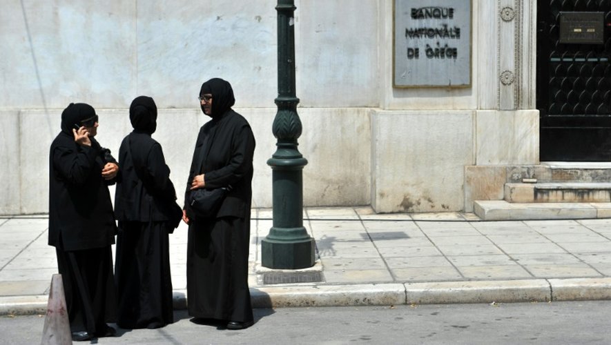 Des religieuses attendent en face de la Banque nationale de Grèce, dans le centre de la ville de Thessalonique