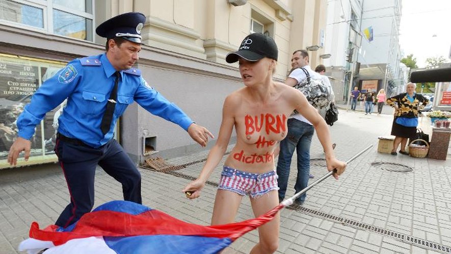 Un officier de police tente d'arrêter une Femen, le 18 juillet 2013 à Kiev